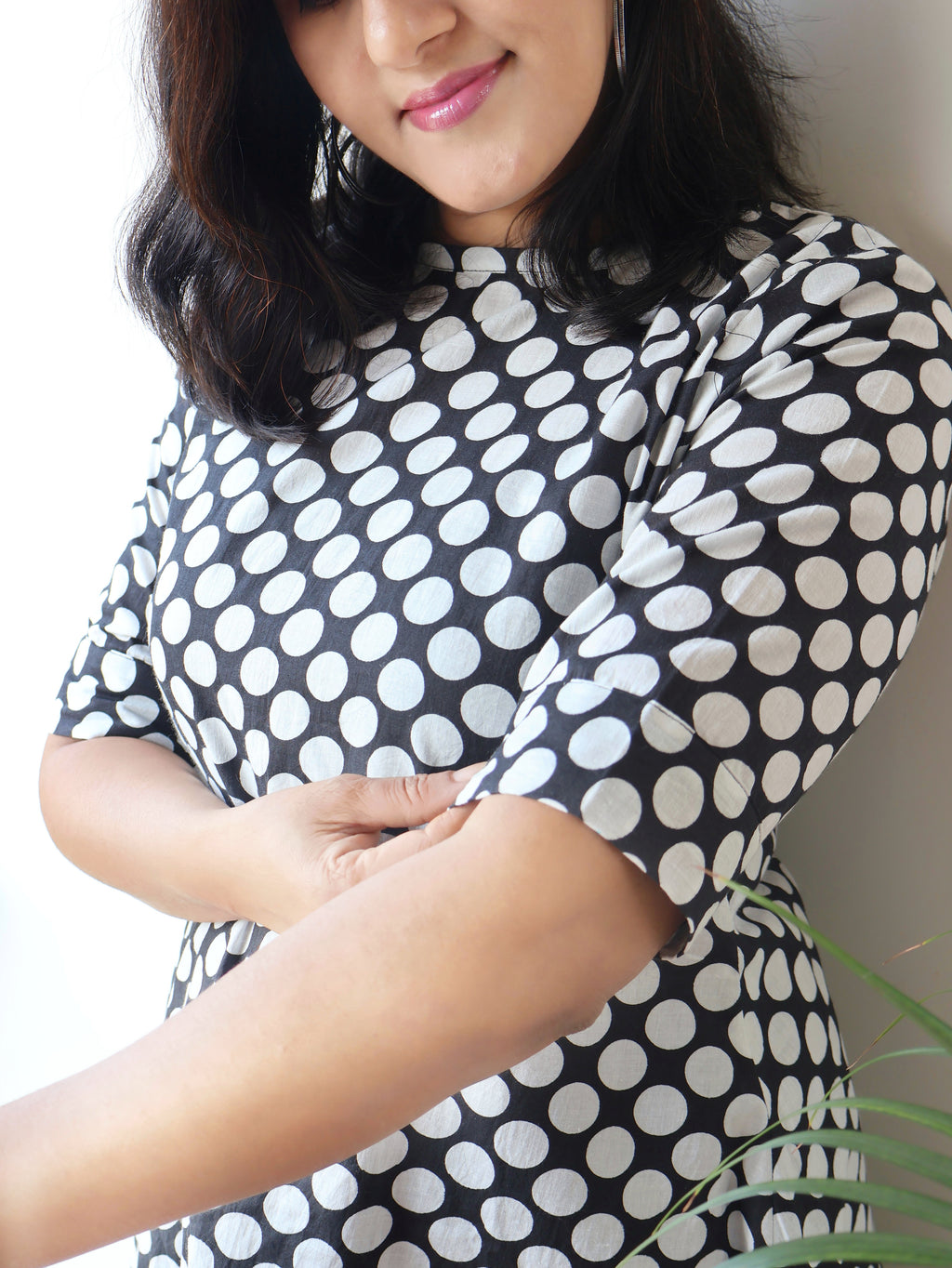 Woman wearing a black and white polka dot dress with a neutral background