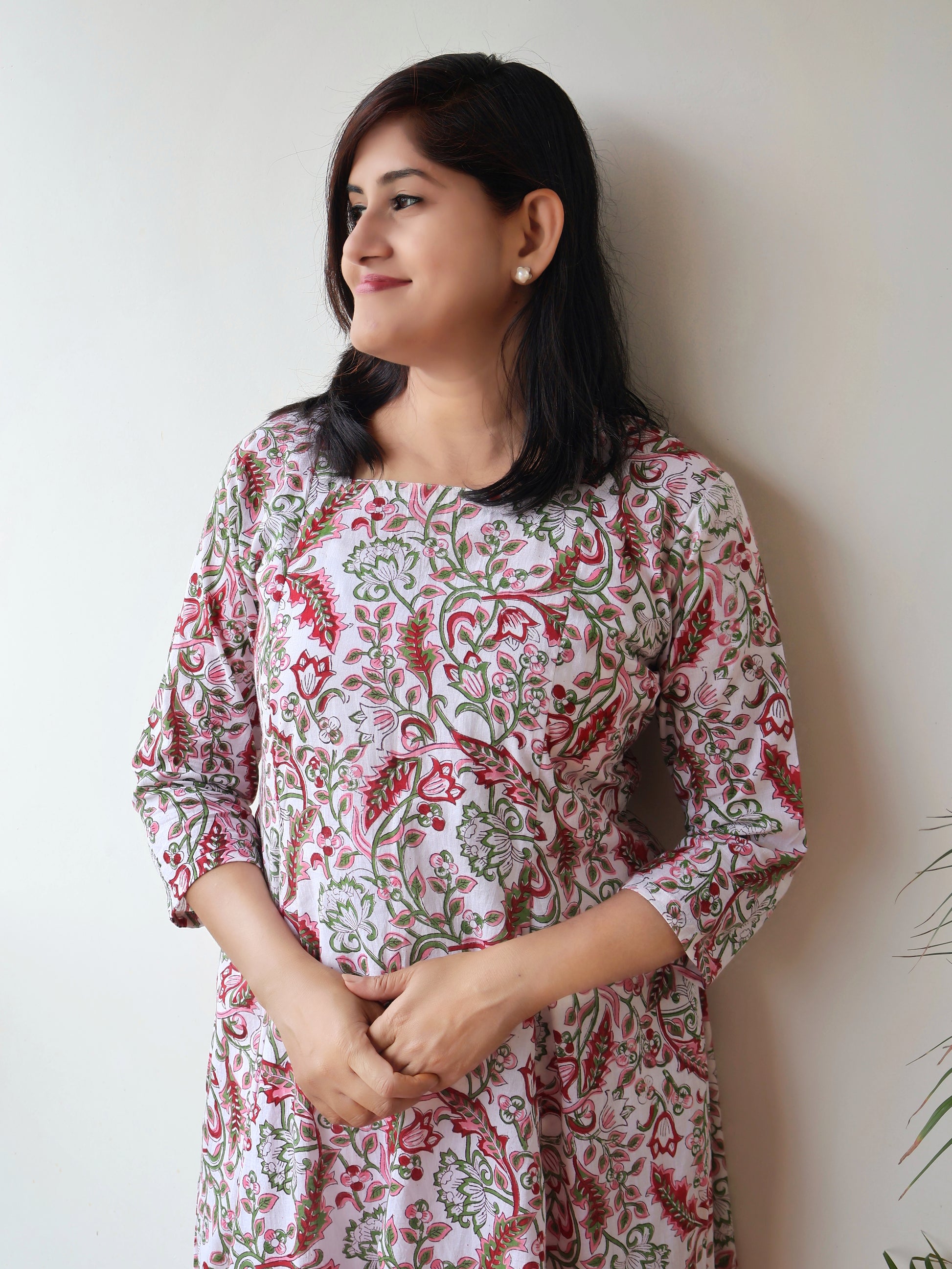 Woman wearing a floral sanganeri  hand block kurta with square neck against a plain background