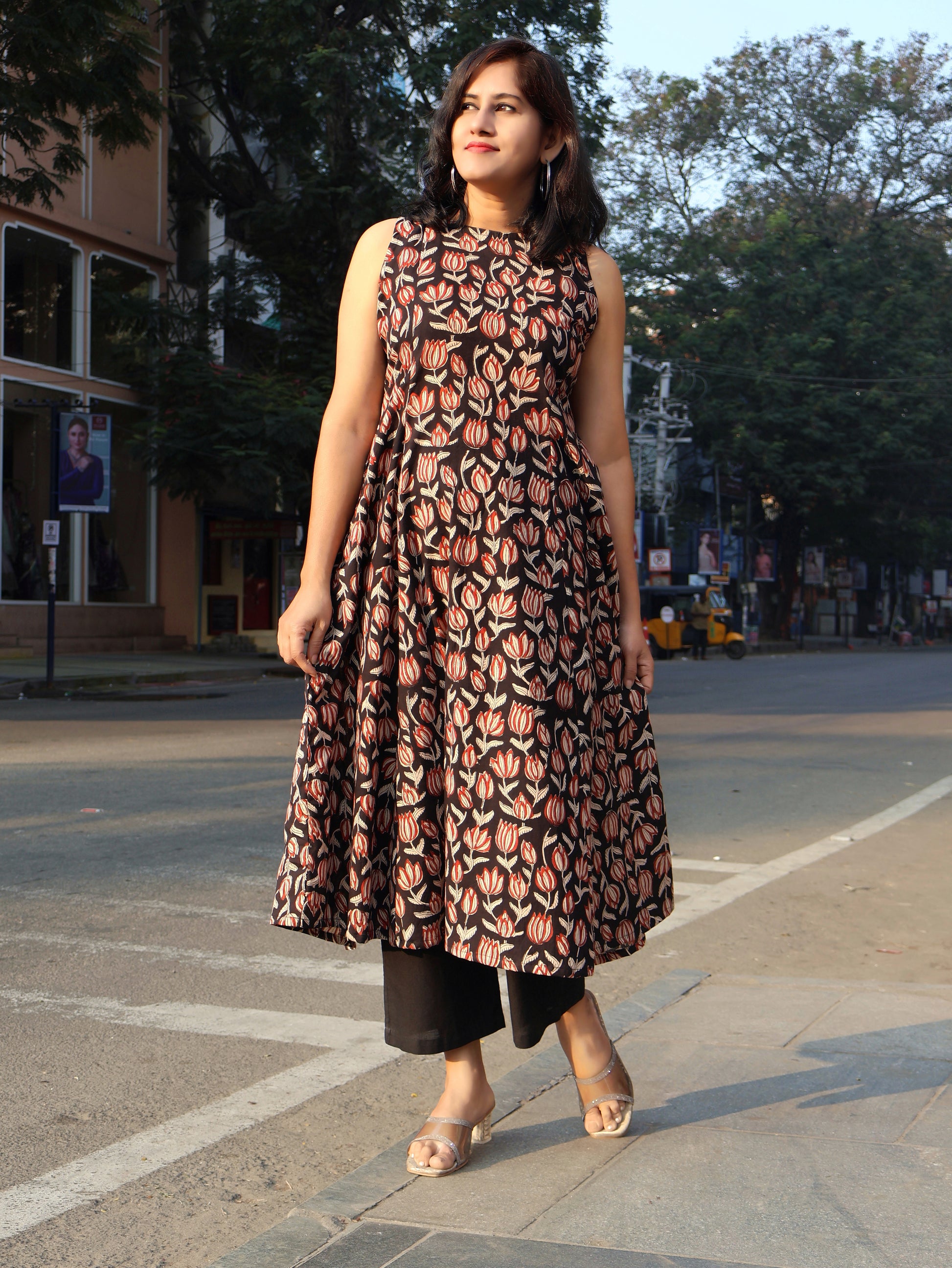Woman wearing a Black Floral sleeveless kurta, standing on a street.
