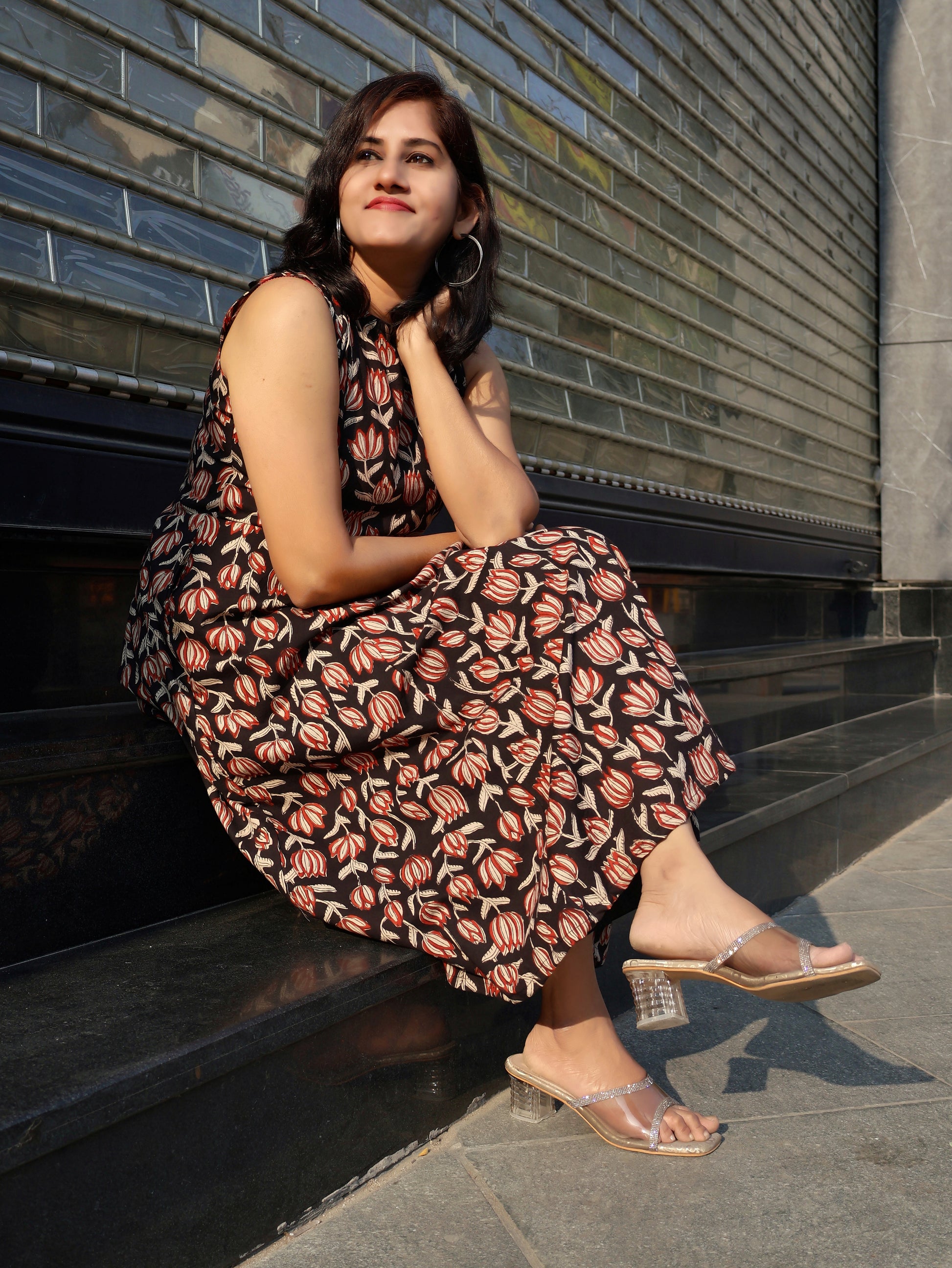 Woman in a pure cotton floral dress sitting on steps outdoors