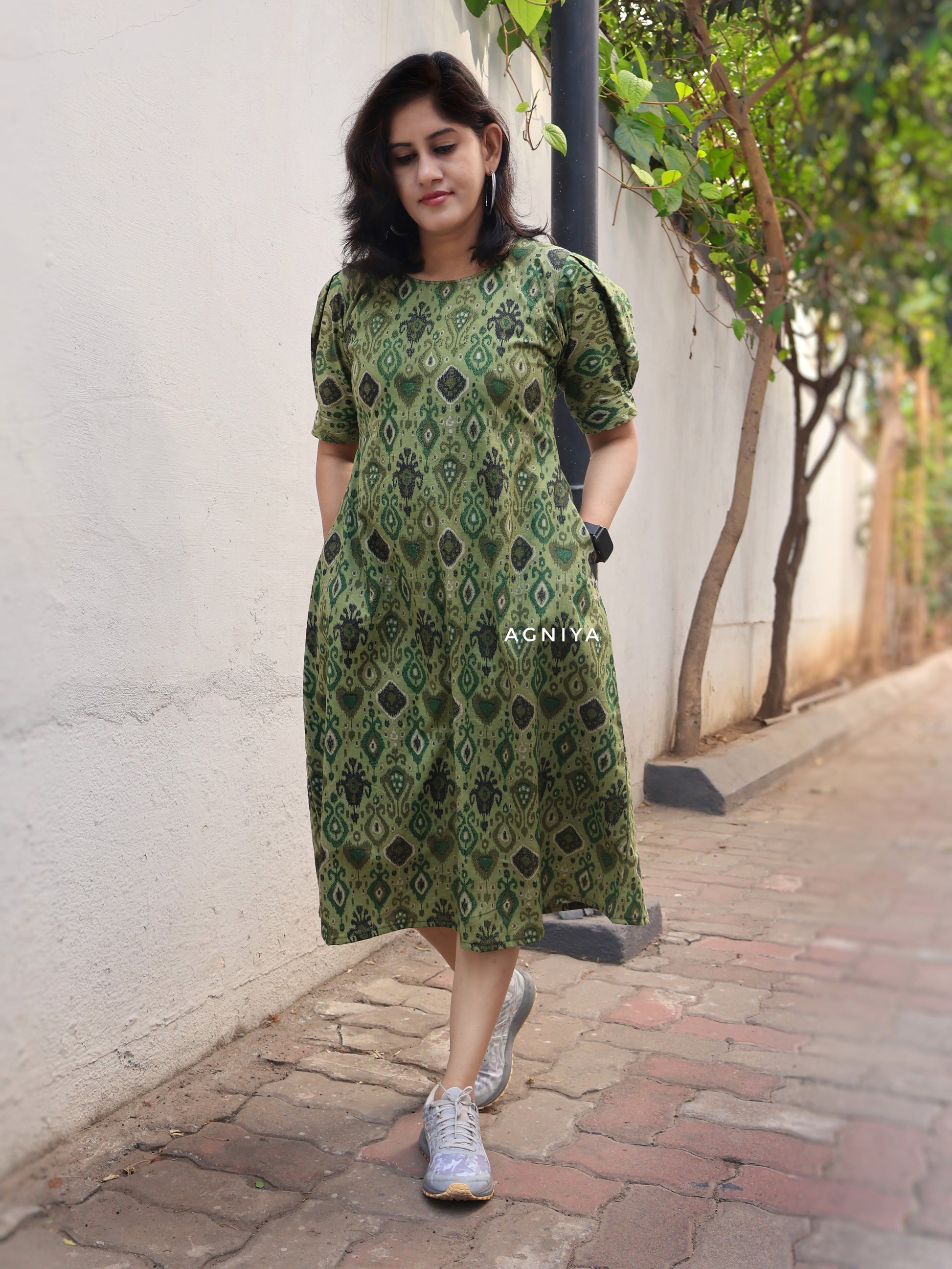 Woman wearing a green patterned dress walking outdoors.