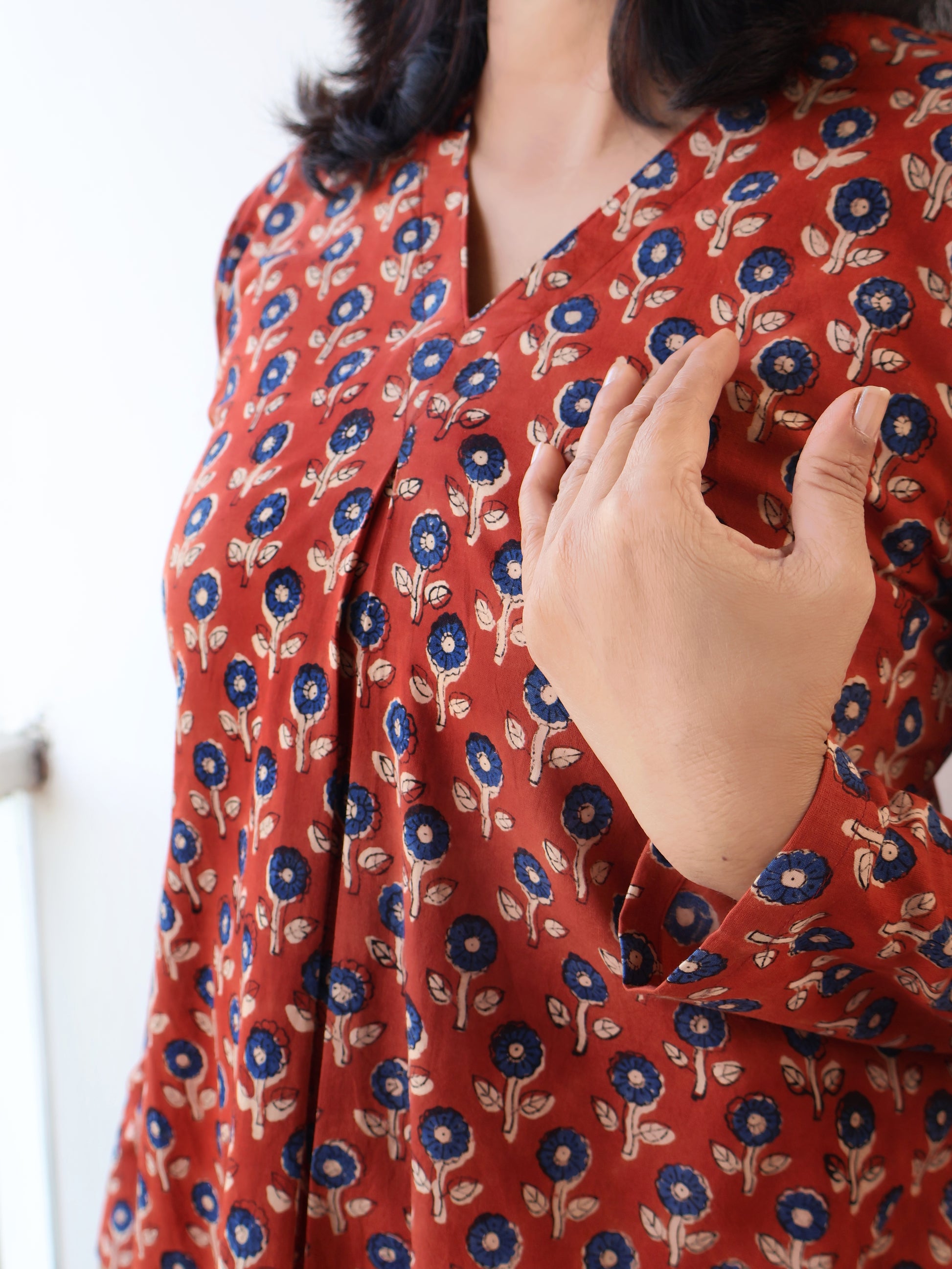 Person wearing a red floral patterned kurta with a blurred background