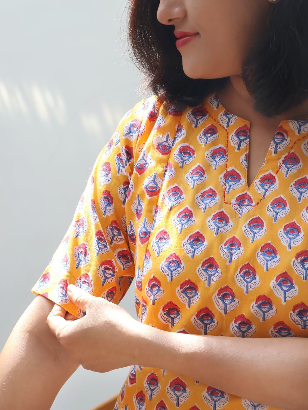 Close-up of hand-embroidered V-neckline on yellow Sanganeri block print cotton kurta